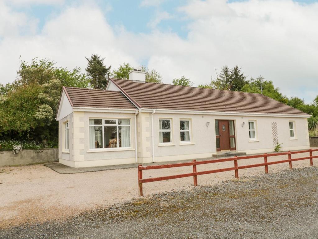 una pequeña casa blanca con una valla roja en Creeslough View, en Creeslough