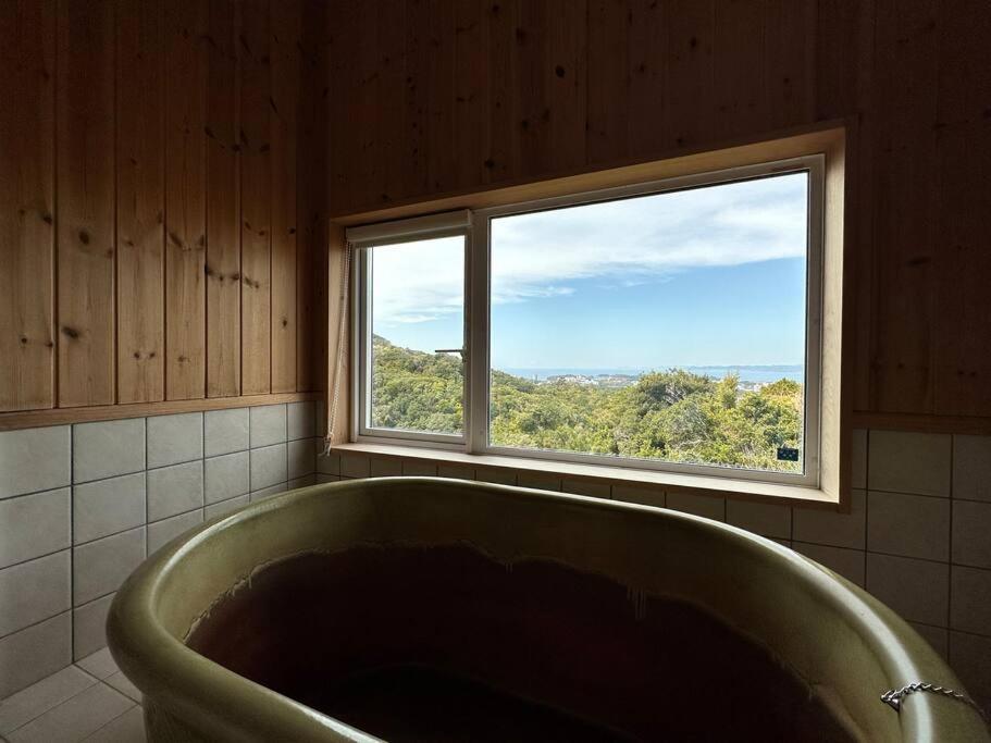 La salle de bains est pourvue d'une baignoire et d'une fenêtre. dans l'établissement SHIRAHAMA condominium D-157, à Kanayama