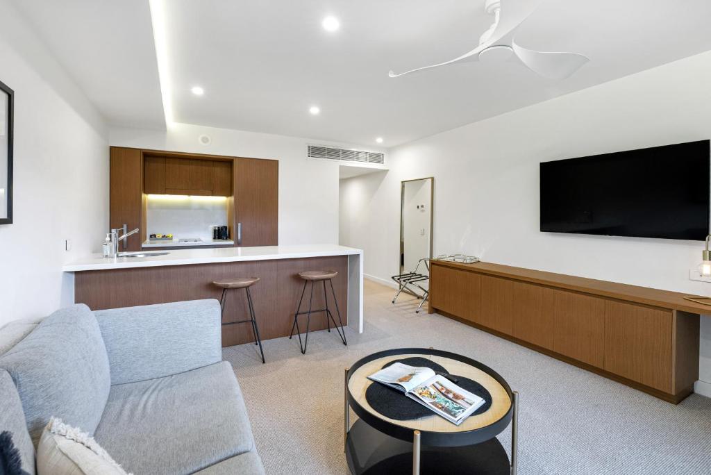 a living room with a couch and a tv and a kitchen at Sapphire Suite- Family friendly in Cairns