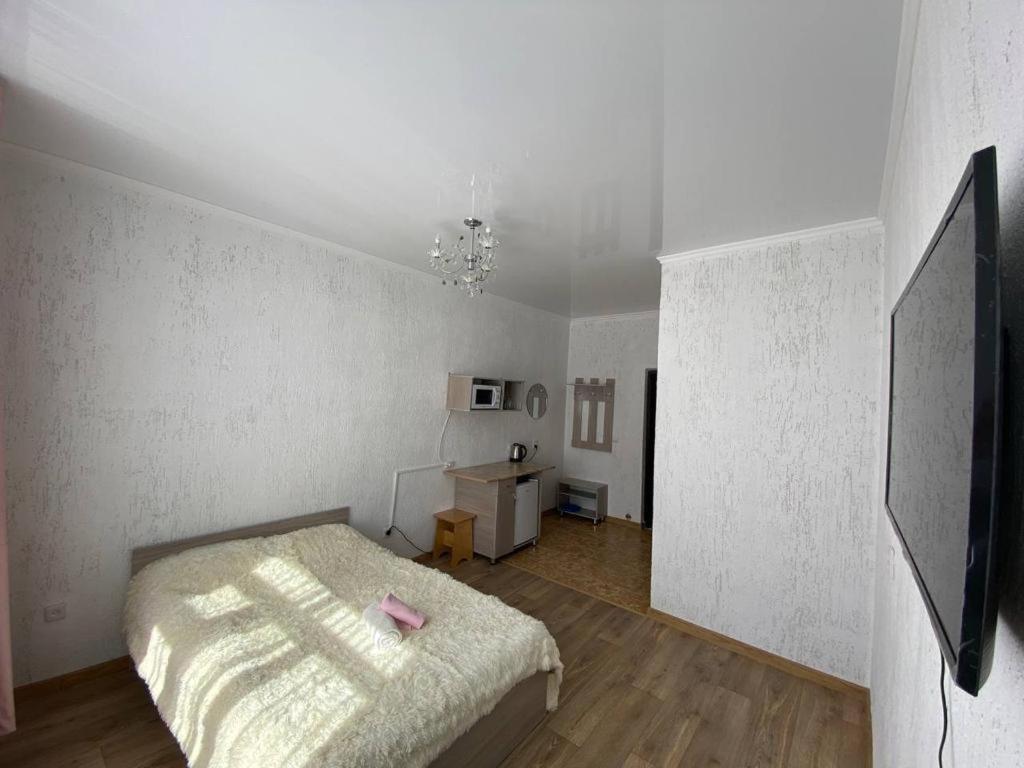 a white bedroom with a bed and a desk at Квартира-студия недорого напротив парка Металлургов in Ustʼ-Kamenogorsk