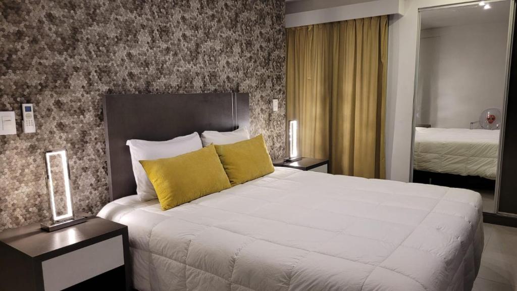 1 dormitorio con 1 cama blanca grande con almohadas amarillas en Be Haus Temporary Apartments en San Luis
