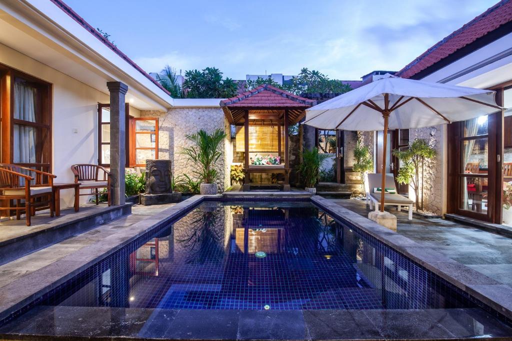 Sanur Beach Villa - 3BR Private Pool في سانور: مسبح داخلي في منزل فيه مظلة