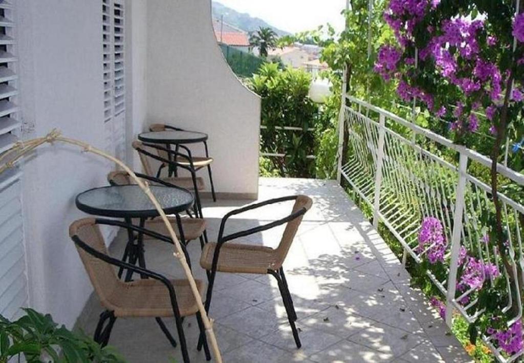 three tables and chairs on a balcony with purple flowers at Josip II - 150 m from beach in Baška Voda