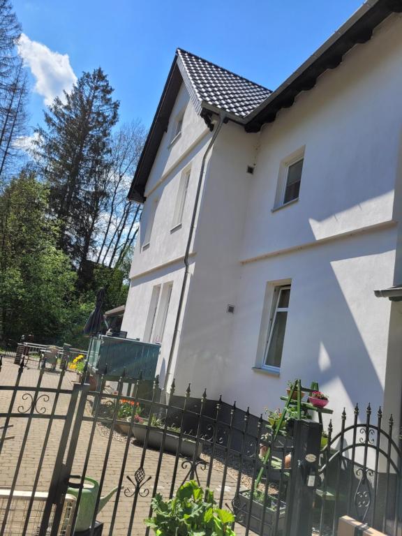 una casa blanca con una valla negra en Eulennest bis 10 Personen,Wäsche,Reinigung,Parkplatz inklusive,Kurtaxe wird extra berechnet, en Altenau