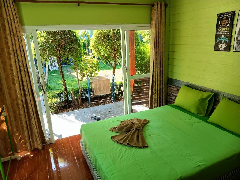 Cama verde en habitación con ventana grande en LUCKY Bungalows Koh Mook en Ko Mook