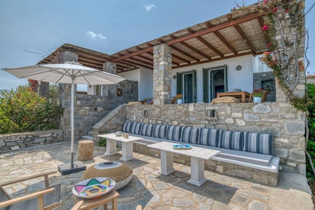 a patio with a bench and an umbrella at Villa Vino - Cycladic Calm in Isterni