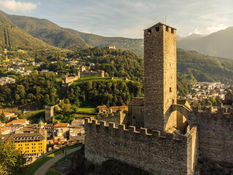 einen Schlossturm mit einer Stadt im Hintergrund in der Unterkunft Hotel Gamper in Bellinzona