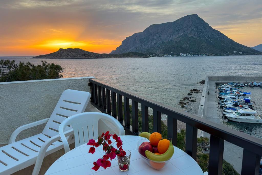una mesa con fruta en el balcón con vistas a la puesta de sol en Pelagos Seafront Accommodation - Maria, en Myrties