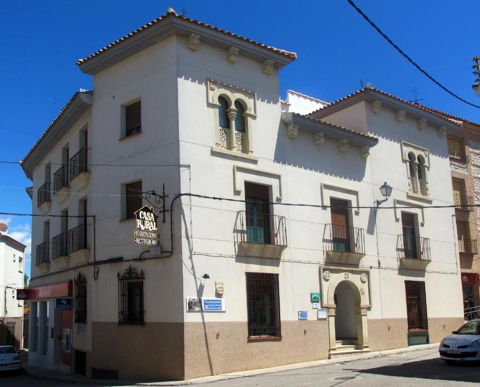 Casa Rural Cuatro de Oros في Santa Cruz de la Zarza: مبنى ابيض كبير على شارع المدينة