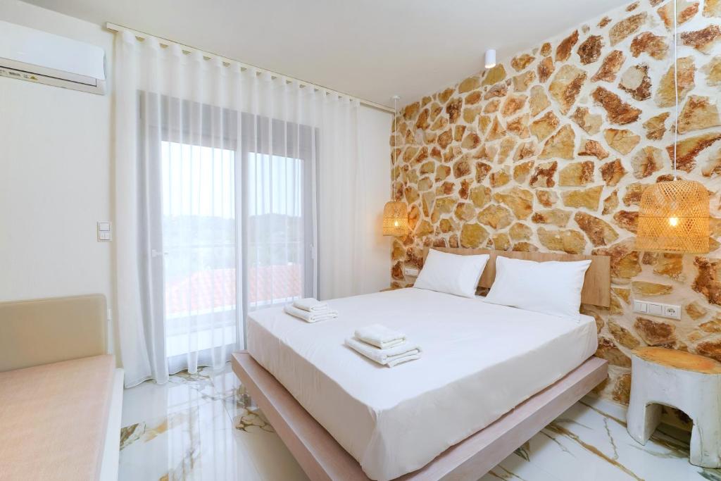 a bedroom with a white bed and a stone wall at Athina Palace Luxurious Appartments in Potos
