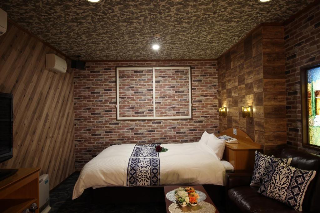 una camera con letto e muro di mattoni di 大人のホテルドルフィア a Daisen