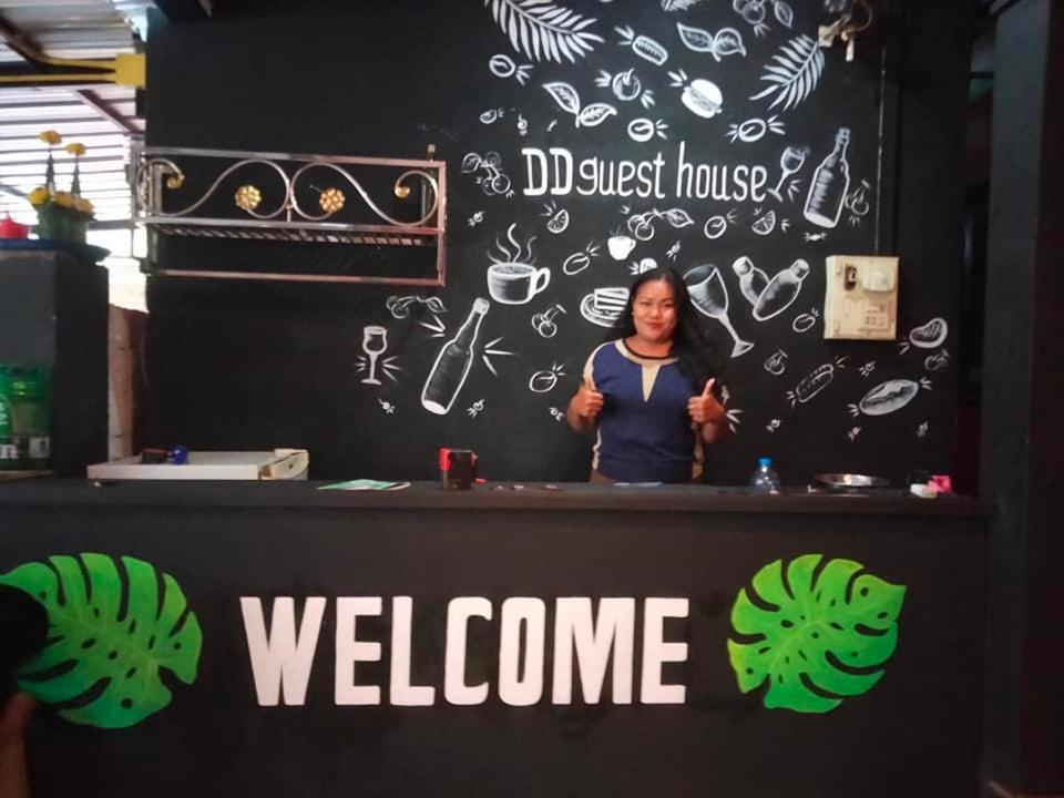 a woman standing behind a counter with a welcome sign at DD Guest House in Pakse