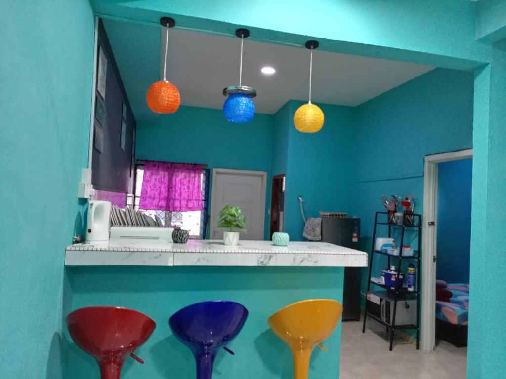 a blue kitchen with colorful stools at a counter at Awani homestay in Semporna