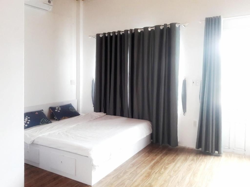 um quarto com uma cama branca e cortinas pretas em Hồng Dương Villa Homestay - phòng đôi view sông Hương trung tâm thành phố #102 em Hue
