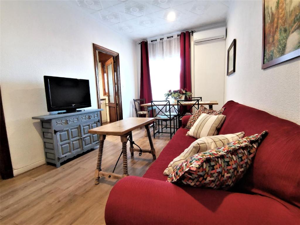 a living room with a red couch and a television at Casa Cervantes Toledo in Toledo