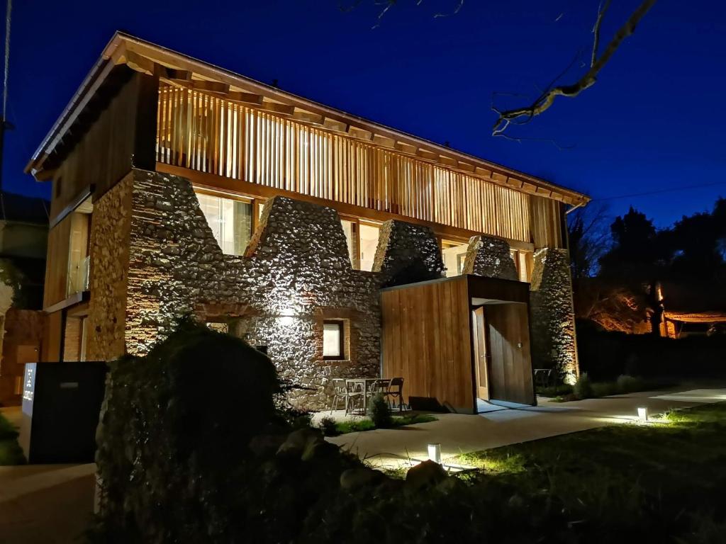 una casa de piedra con fachada de madera por la noche en Apartamentos La Santilar, en Llanes