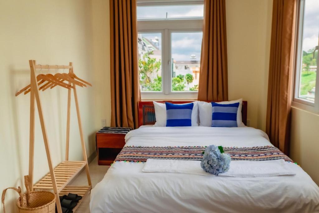 een slaapkamer met een bed met blauwe kussens en een raam bij Bòn Stay Đà Lạt in Da Lat