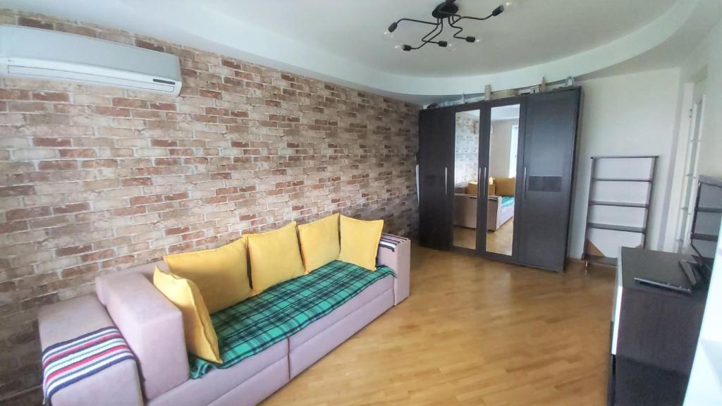 salon z kanapą i ceglaną ścianą w obiekcie Апартаменти поруч з метро Лівобережна w Kijowie