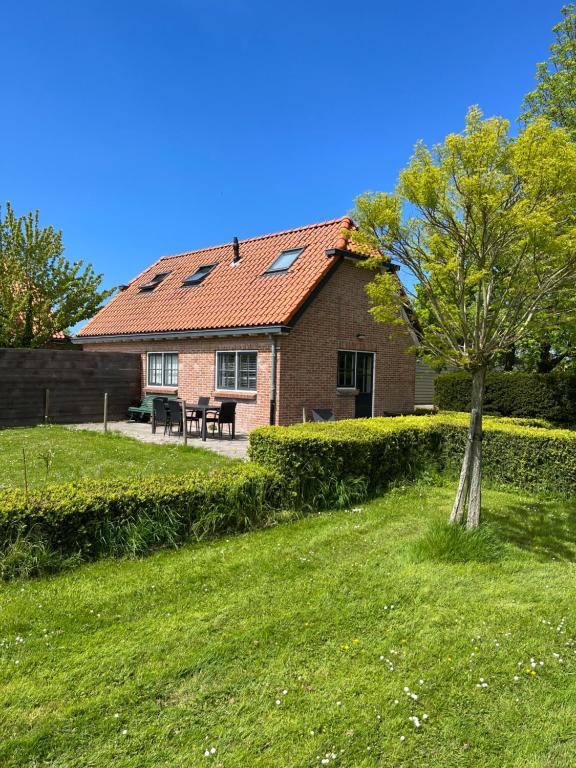 een huis met een tafel en een boom in de tuin bij Hèt Koetshuis in Oostkapelle