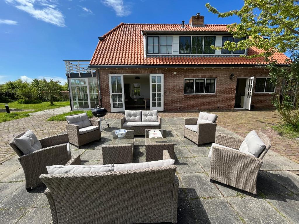 a patio with wicker chairs and tables in front of a house at Het Landhuis in Oostkapelle
