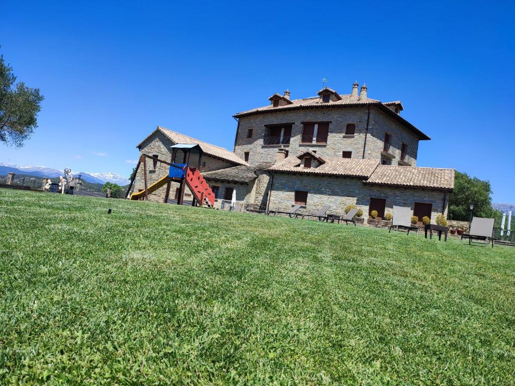 a large building on top of a green field at Casas Pirineo, Ainsa in Aínsa