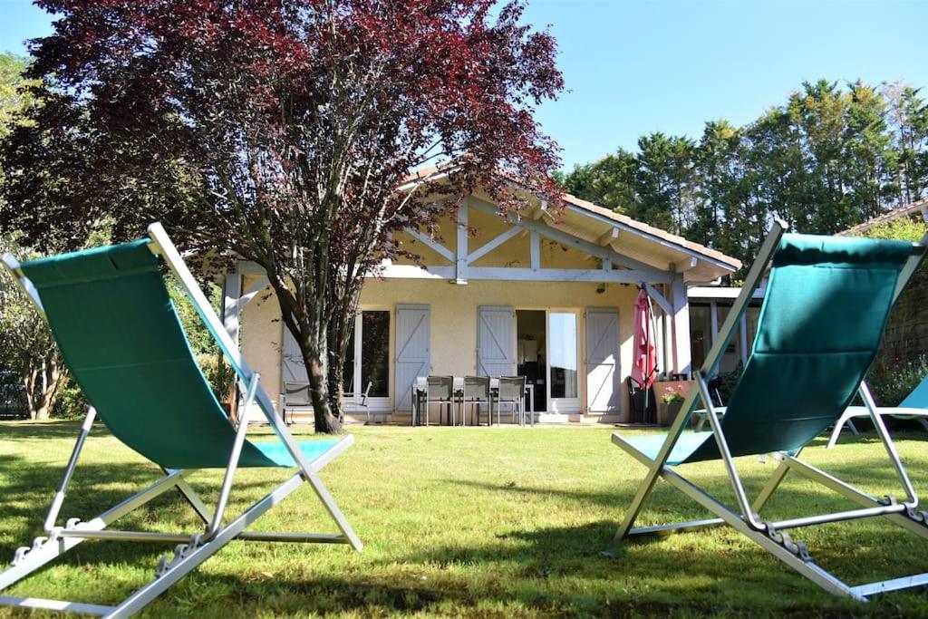 deux chaises assises dans l'herbe devant une maison dans l'établissement Villa Sea, Surf & Golf - Saubion - Hossegor, à Saubion