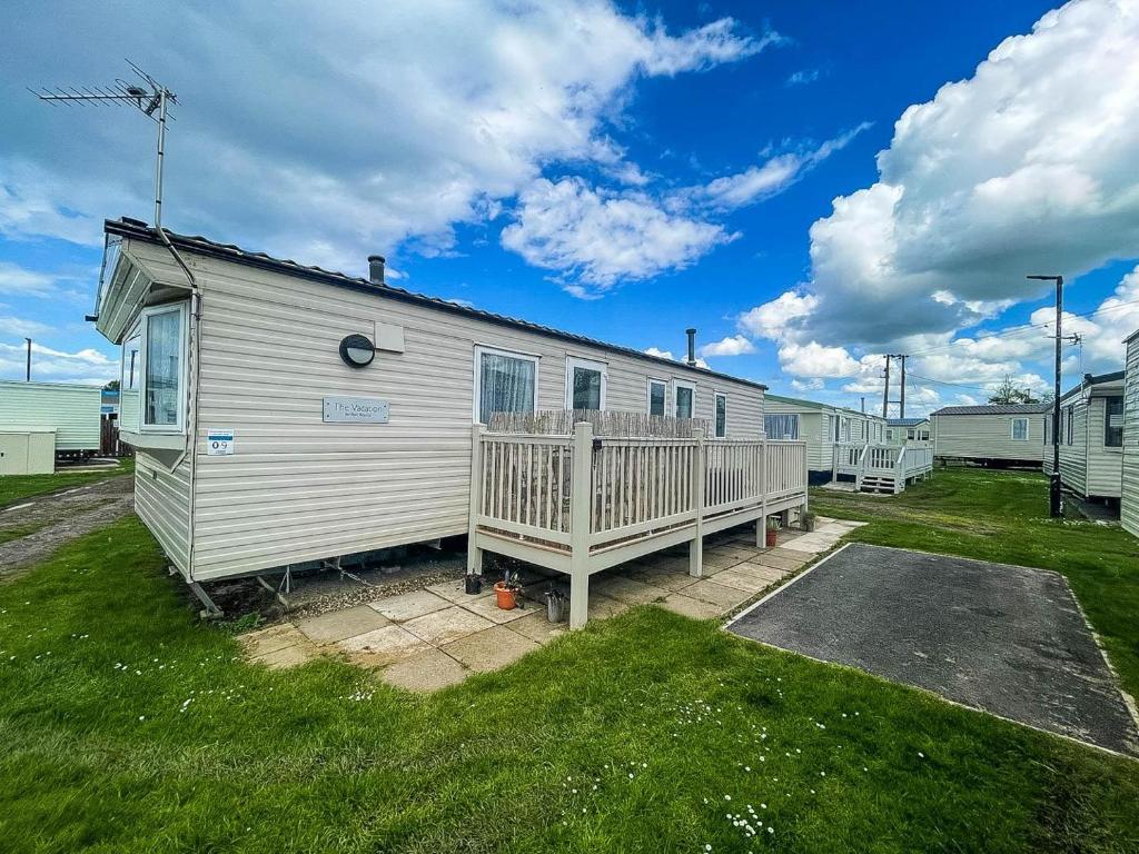 a white house with a porch and a yard at Lovely 6 Berth Caravan With Decking To The Side In Heacham Ref 21009i in Heacham