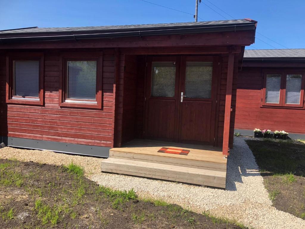 Cette petite maison dispose d'une porte en bois et d'une terrasse couverte. dans l'établissement WOMOCAMP Holzhütte 2, à Saulkrasti