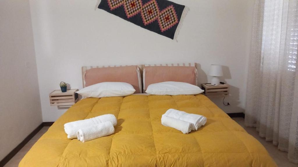 1 cama amarilla grande con 2 toallas blancas. en Bayekou, en Paceco