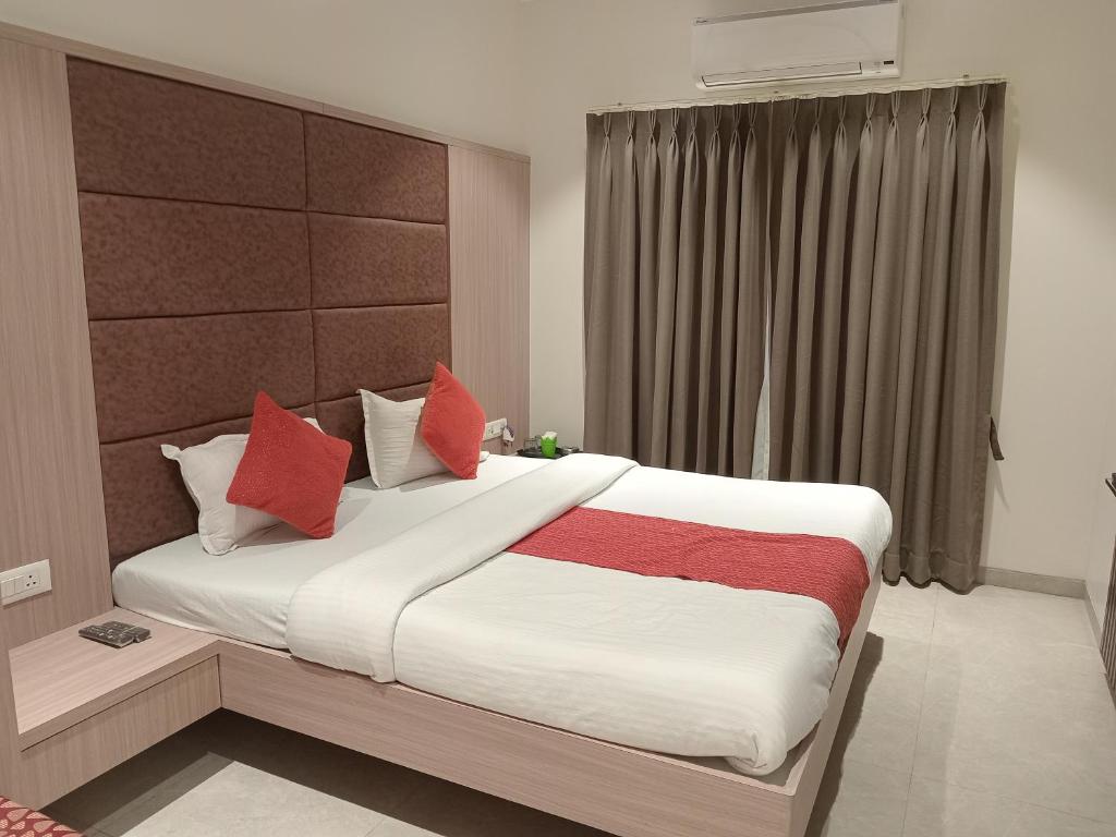 a bedroom with a large bed with red pillows at Hotel Rajshree in Ahmadnagar