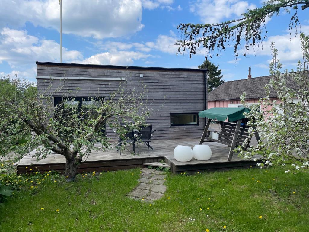 ein Haus mit einer Terrasse mit einem Tisch und einem Picknicktisch in der Unterkunft Modernt Attefallshus in Ängelholm