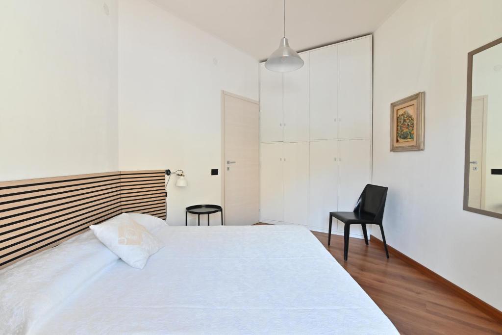 a bedroom with a white bed and a black chair at Artemis Kalaris Home in Cagliari