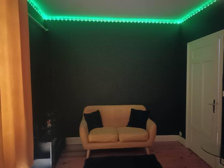 un sofá con 2 almohadas en una habitación con luces verdes en L'appart de Babou REZ DE CHAUSSEE parking free draps wifi, en Thiers