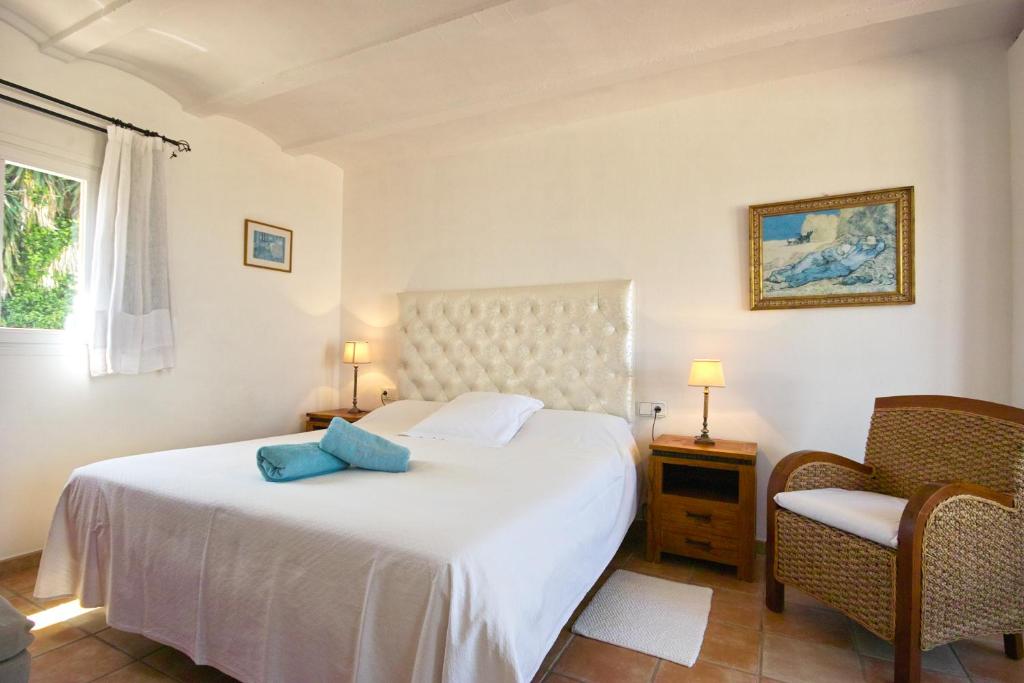 a bedroom with a white bed and a chair at Hotel Rural Can Maries in Puerto de San Miguel