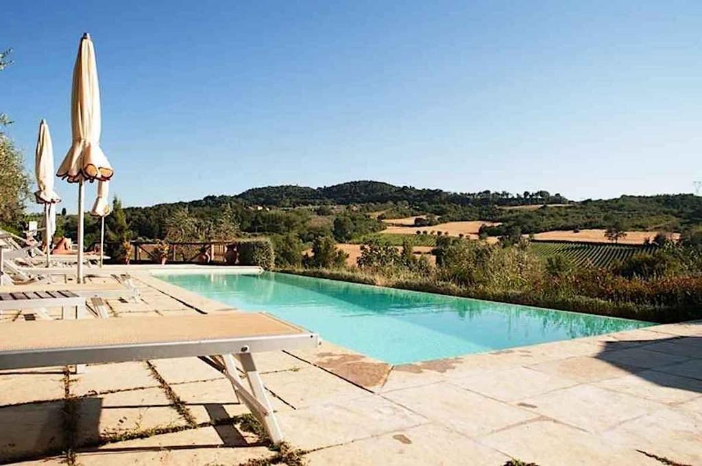 a swimming pool with a table and umbrellas at I Borghi in San Gimignano