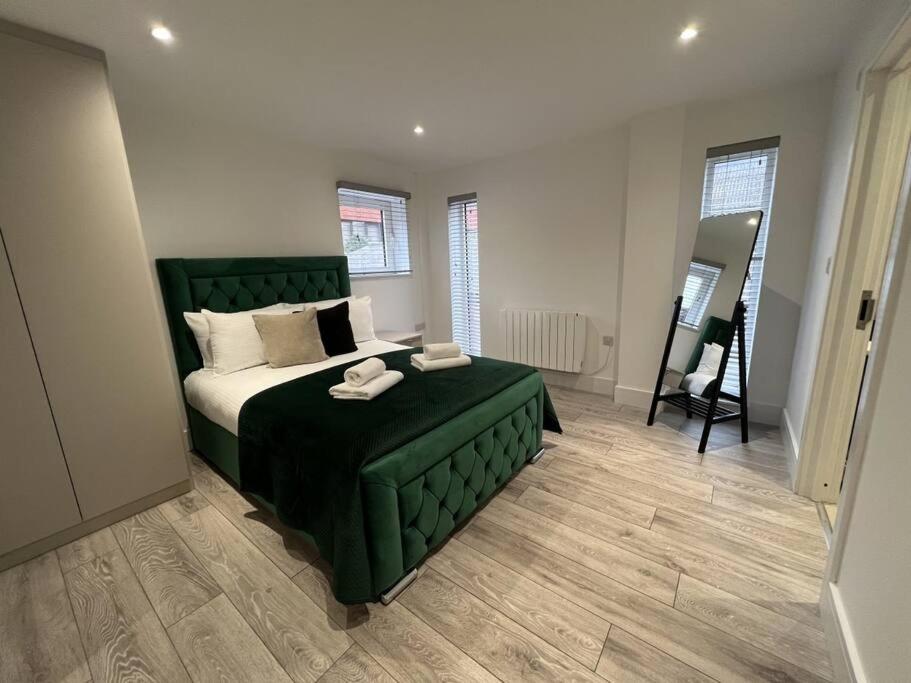 a bedroom with a green bed and a mirror at Mustafa House By E2M Stays - 1 & 2 Bedroom Stunning Apt in Central Town in Camberley