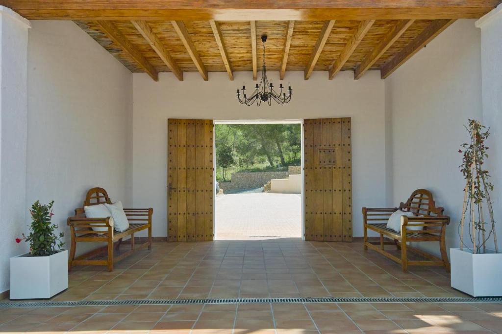 a room with two benches and a door with a chandelier at Hotel Rural Can Maries in Puerto de San Miguel