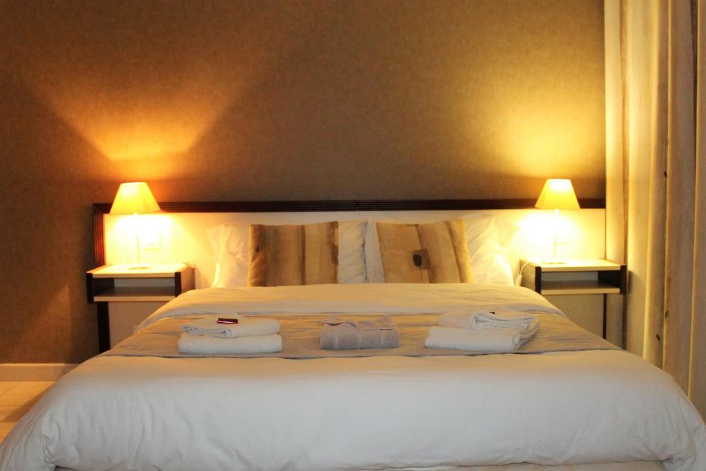 a bedroom with a large white bed with two lamps at Village Club Thalassa in Mèze