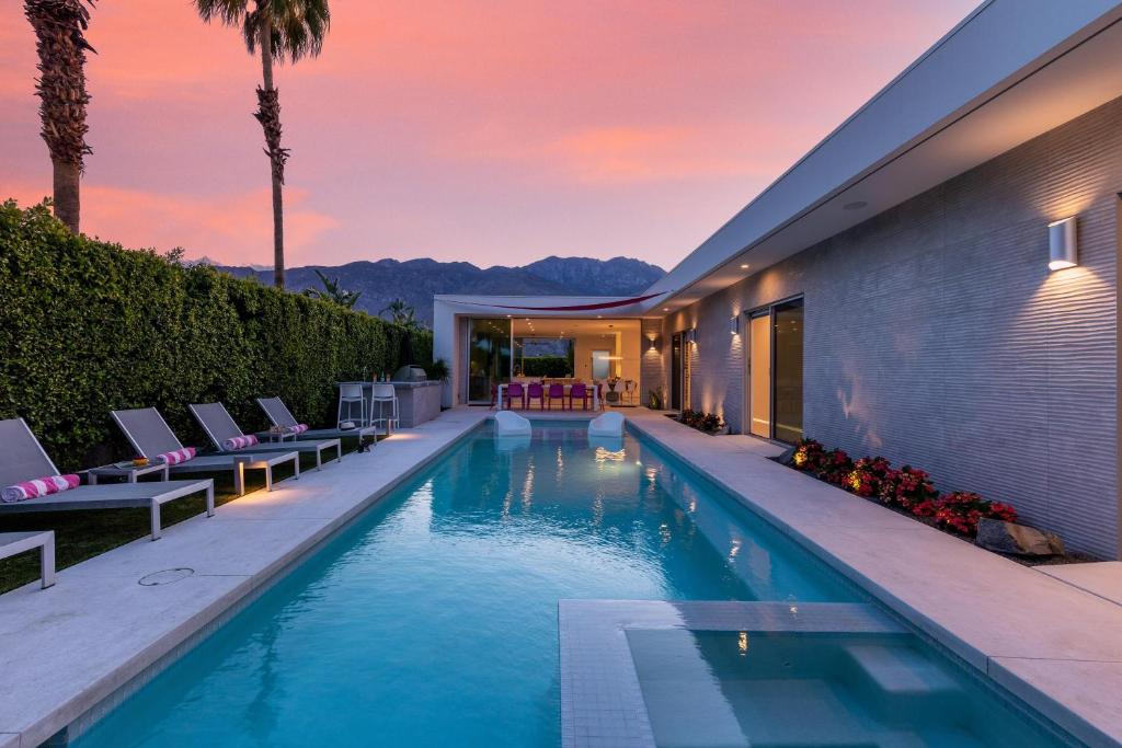 uma piscina com espreguiçadeiras e uma casa em Modern Luxe em Palm Springs