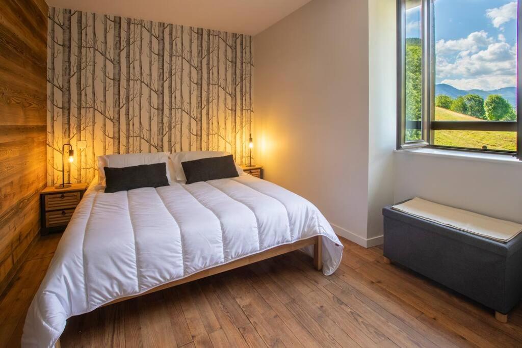 a bedroom with a white bed and a window at Gîte d&#39;AURE. Classé en meublé 4 étoiles. 