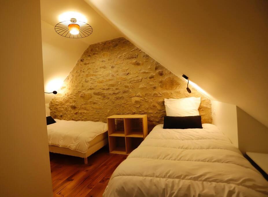 a bedroom with two beds and a stone wall at Gîte d&#39;AURE. Classé en meublé 4 étoiles. 