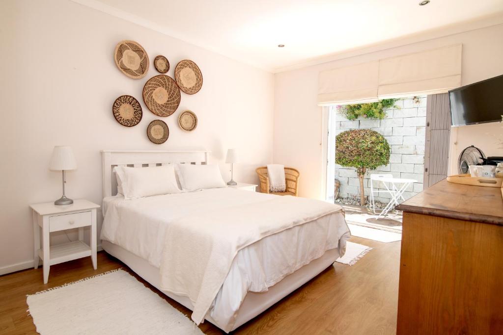 a white bedroom with a bed and a window at Camps Bay Guest Suite with private pool in Cape Town