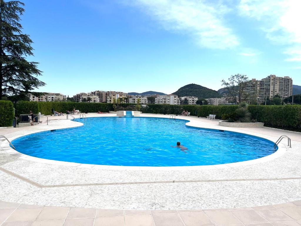 une personne nageant dans une grande piscine bleue dans l'établissement Appartement Cosy Piscine Mandelieu, à Mandelieu-la-Napoule