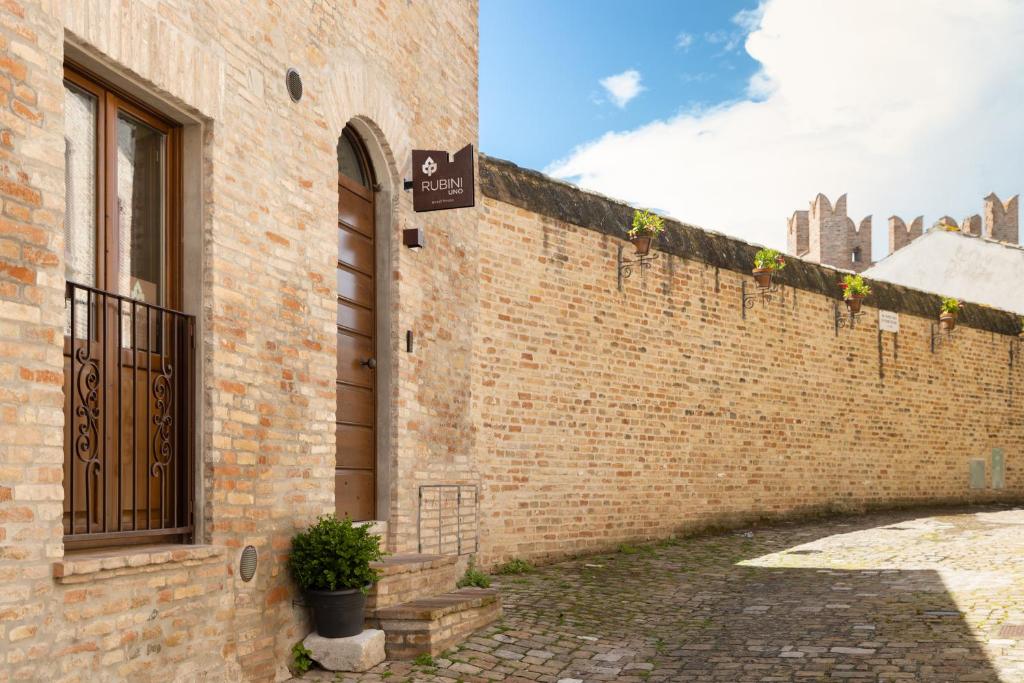 uma parede de tijolos com uma porta e um vaso de plantas em Rubini Uno Guest House em Gradara