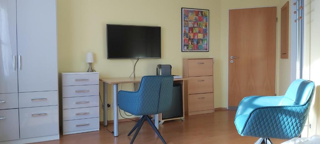 Habitación con escritorio con 2 sillas y TV. en Zimmer mit Gartenblick, en Colonia