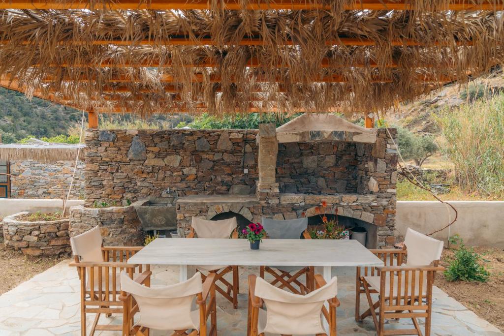 a table and chairs in front of a stone fireplace at Houses at Chrisopigi Sifnos in Chrisopigi