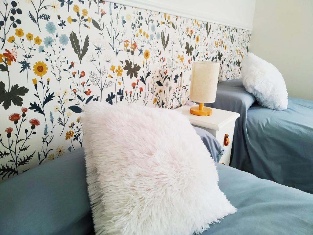 Un dormitorio con una almohada blanca en una cama con un papel pintado de flores en ESPECIAL HOME apartamento reformado 6 huéspedes en Avilés