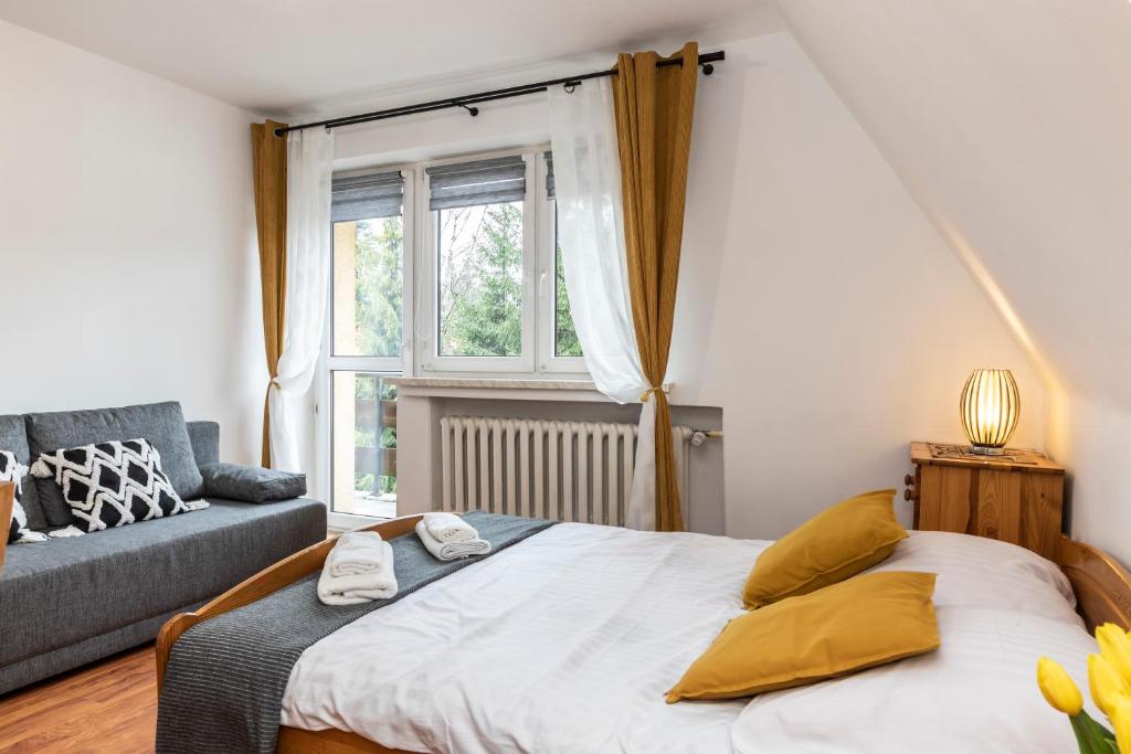 a bedroom with a bed and a couch and a window at Pensjonat Góraleczka-Kościelisko in Kościelisko