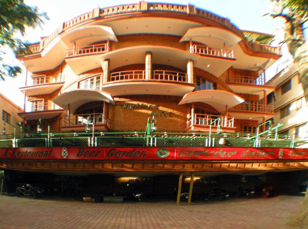 een groot gebouw met een rood bord ervoor bij Parklane Hotel in Mysore