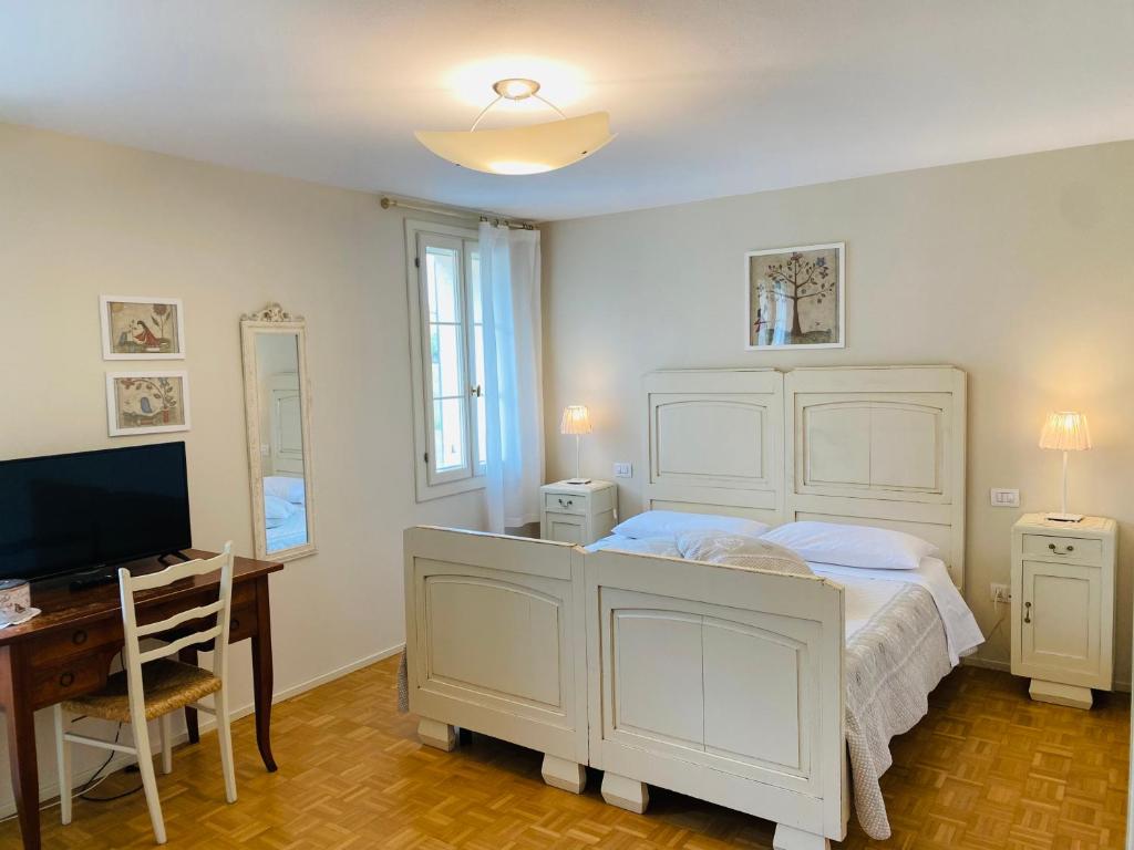 a bedroom with a bed and a desk and a television at La Fabbrica Delle Idee B&B in Fonte